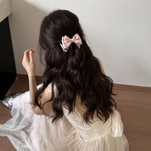 Detail of a French style pink polka dot bow hair comb in dark wavy hair.