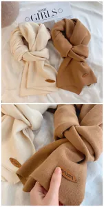 Detailaufnahme von weich gestrickten Schals in Creme und Camel mit Lederetiketten