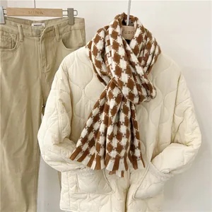 Primer plano de una bufanda de cuadros marrón y blanca sobre una chaqueta acolchada beige.