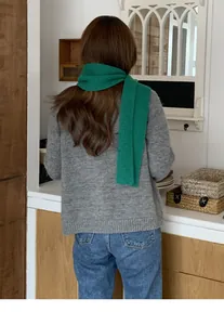 Vista posteriore di una sciarpa a maglia verde abbinata a un maglione grigio caldo