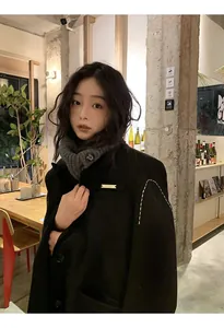 Grey knitted neck warmer with button detail on model in cozy cafe setting