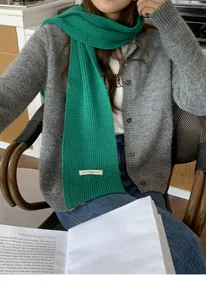 Dettaglio di una calda sciarpa verde a maglia, abbinata con un cardigan grigio raffinato