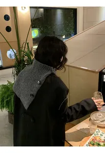 Detail view of a grey retro knitted neck warmer with buttons worn over a coat.