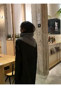 Retro grey knitted button neck warmer scarf paired with a black wool coat in a cafe