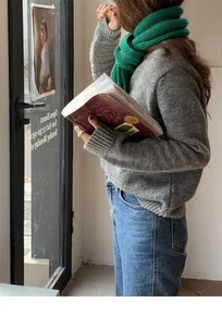Dettaglio di una sciarpa a maglia verde vivace abbinata a un maglione autunnale grigio