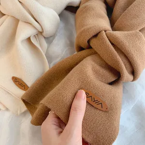 Weiche gestrickte Winterschals in Beige und Camel mit eleganten kleinen Lederetiketten
