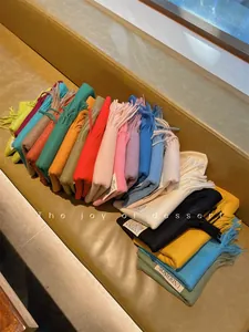 Variety of colorful solid imitation cashmere scarves with tassels arranged on a bench