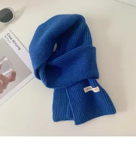 Primo piano di una sciarpa in lana lavorata a maglia blu reale con etichetta minimalista