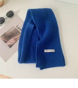 Primo piano di sciarpa in maglia blu con un dettaglio di etichetta minimalista.