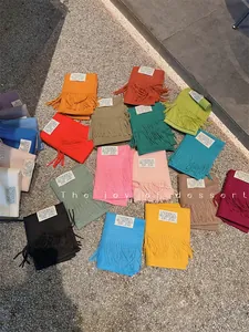 Collection of colorful solid faux cashmere scarves with tassels on outdoor gravel ground