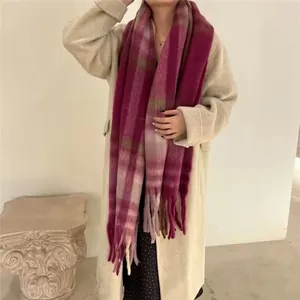 Detailed view of thick plaid and magenta tassel scarf paired with a beige winter coat