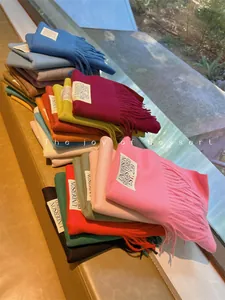 Detailed view of colorful solid cashmere-like scarves with fringe edges and brand labels