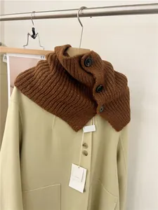 Detailed view of a brown ribbed knitted neck warmer collar featuring three large black buttons