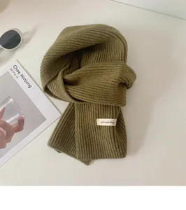 Trama dettagliata di una sciarpa in maglia verde scuro con etichetta in tessuto bianco