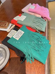 Colorful fringed imitation cashmere scarves displayed on a table with a dessert