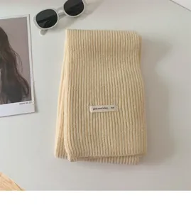 Primo piano di una sciarpa a maglia crema minimalista con etichetta tessile