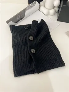 Close-up detail of a black ribbed knitted neck warmer with vintage button closure