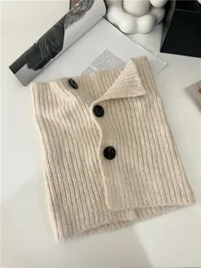 Detail view of cream knitted neck warmer with three black buttons and ribbed texture