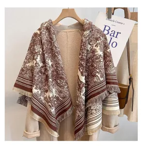 Detail of vintage landscape print shawl draped over a beige coat on a hanger
