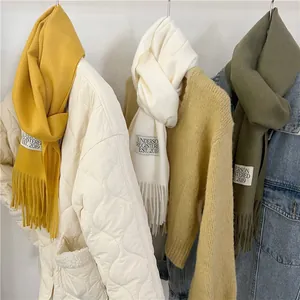 Detail view of three soft faux cashmere scarves in yellow, white, and olive green colors