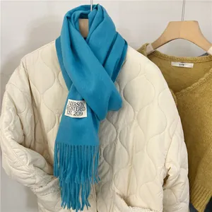 Close-up of bright blue soft cashmere-like scarf with Anderson label and fringe details.