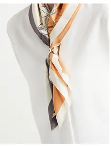 Detail der eleganten X-förmigen goldenen Seidenschal-Schnalle mit gemustertem Schal.