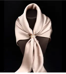 Detailansicht einer eleganten goldener X-förmigen Seidentuch-Schnalle in Champagner