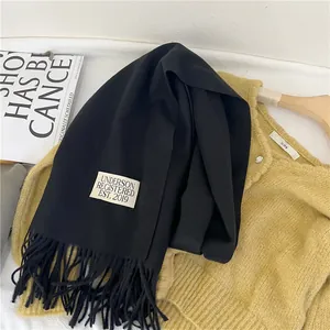 Close-up of a soft black imitation cashmere scarf with fringed edges and decorative label