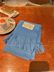 Soft solid blue imitation cashmere scarf with tassels on a wooden table