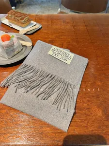 Close-up of a soft grey faux cashmere scarf with fringe details and a vintage woven label.