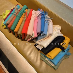 Vibrant solid color imitation cashmere scarves with tassels in various trendy hues.