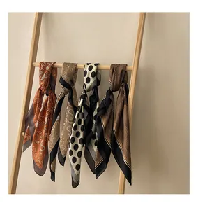 A collection of four vintage patterned small square silk scarves displayed on a wooden ladder
