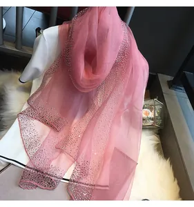 Vue détaillée d'une écharpe en soie rose transparente ornée de strass brillants