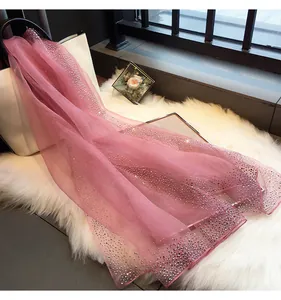 Détail d'une écharpe en soie rose élégante avec un motif dégradé en strass brillants