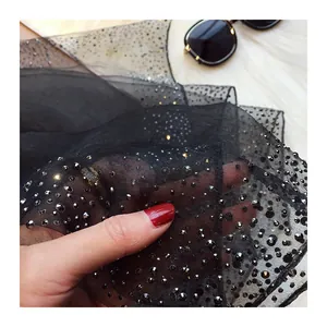 Gros plan d'une écharpe en maille noire avec strass scintillants montrant la texture du tissu