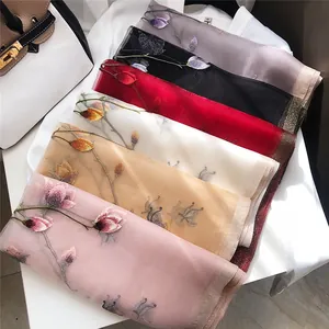 Macro view of several elegant silk scarves featuring intricate floral embroidery details
