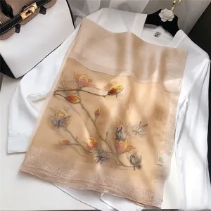 Detailed view of champagne silk scarf featuring intricate floral and butterfly embroidery