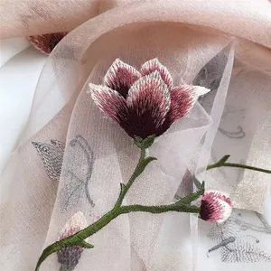 Detailed embroidery of a purple magnolia flower on a lightweight pink silk wool scarf.