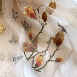 Close-up of elegant floral and butterfly embroidery on a sheer beige silk wool scarf