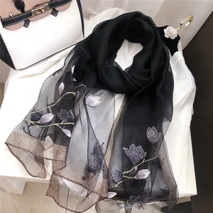 Close-up of elegant black scarf with purple floral embroidery and metallic edges
