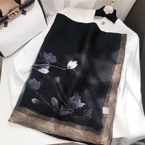 Close-up of elegant black scarf with butterfly embroidery and shimmering gold border