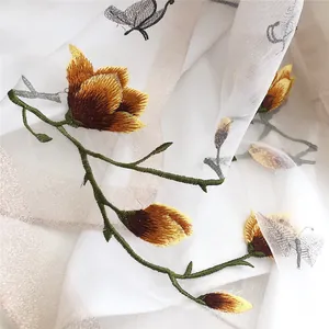 Close-up of elegant embroidery detail featuring floral and butterfly motifs on a white scarf