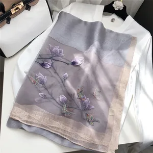 Macro detail showing exquisite butterfly and flower embroidery on a silk wool scarf
