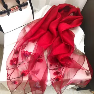 Detail view of an elegant red silk wool shawl with floral and butterfly embroidery