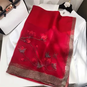 Close-up of elegant red embroidered silk scarf with magnolia and butterfly patterns