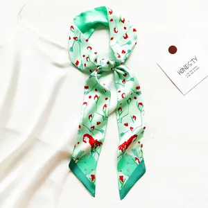 Gros plan d'un long foulard ruban en soie vert menthe aux motifs floraux d'art