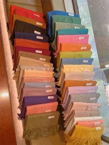 Assorted soft solid color winter scarves with fringe tassels in various vibrant hues.