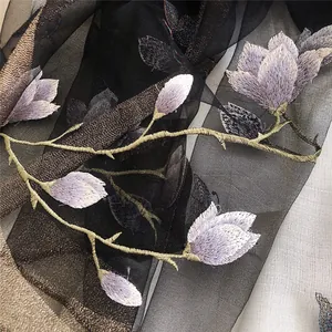 Macro view of exquisite purple magnolia embroidery on a sheer black silk and wool scarf
