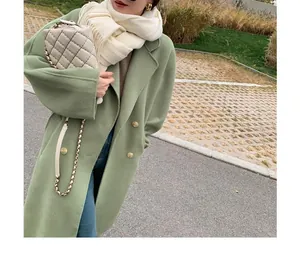 Close-up of cream soft warm scarf with long fringes worn with a green winter coat