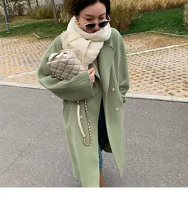 Close-up of a soft cream-colored scarf with tassels worn with a green coat